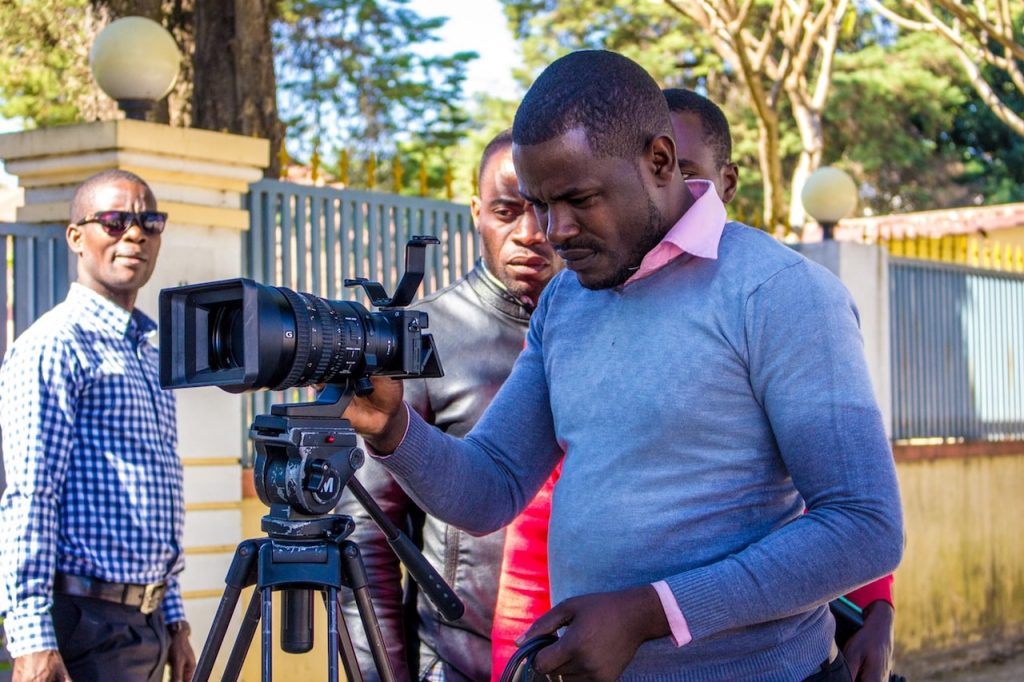 Man in blue sweater holding black dslr camera